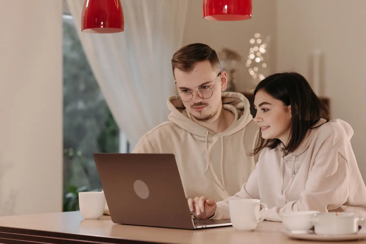 A couple planning a British countryside holiday at a table with a laptop and notes